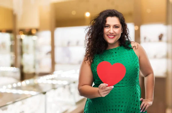 Mujer feliz en vestido verde sosteniendo el corazón rojo —  Fotos de Stock