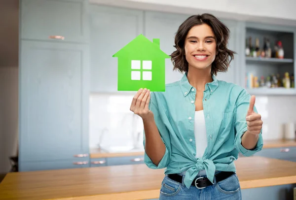 Mulher com casa verde mostra polegares para cima na cozinha — Fotografia de Stock