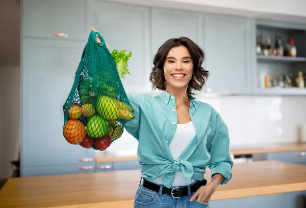 Mujer sonriente feliz con comida en bolsa de red reutilizable —  Fotos de Stock