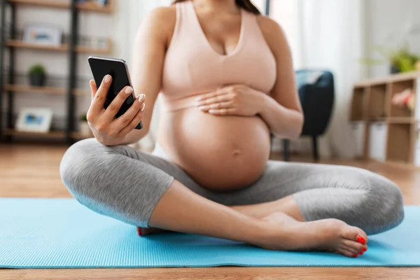 Close up of pregnant woman with phone on yoga mat — Stock Photo, Image