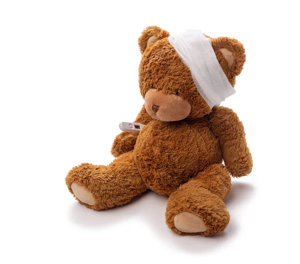 Teddy bear toy with bandaged head and thermometer — Stock Photo, Image