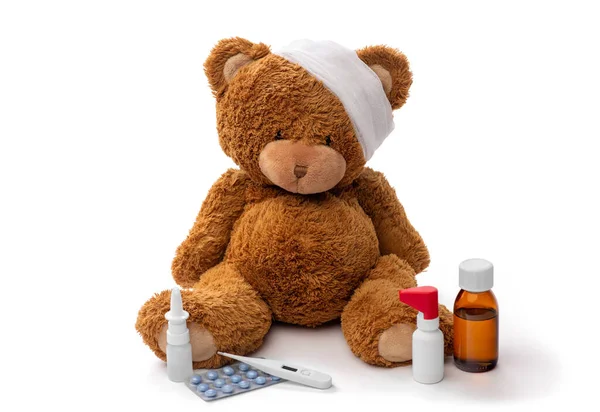 Teddy bear toy with bandaged head and medicines — Stock Photo, Image