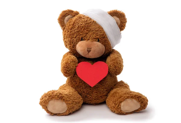 Ursinho de pelúcia brinquedo com cabeça enfaixada e coração vermelho — Fotografia de Stock