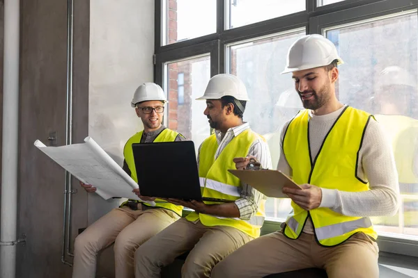 Мужчины-архитекторы в шлемах с ноутбуком в офисе — стоковое фото