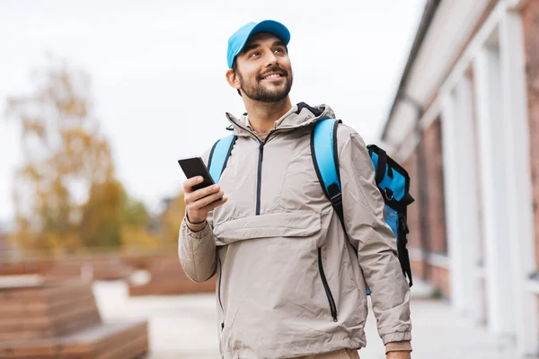 Zusteller mit Telefon und Thermobeutel in der Stadt — Stockfoto