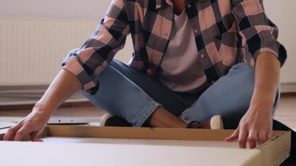 Женщина распаковывает новые детали мебели дома — стоковое видео