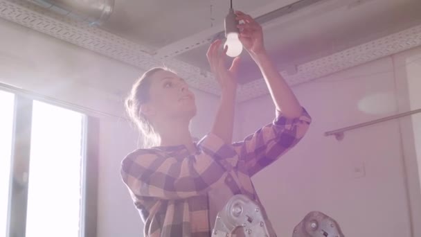 Vrouw veranderende gloeilamp in nieuw huis — Stockvideo