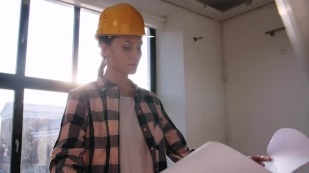 Vrouw in helm met blauwdruk in nieuw huis — Stockvideo