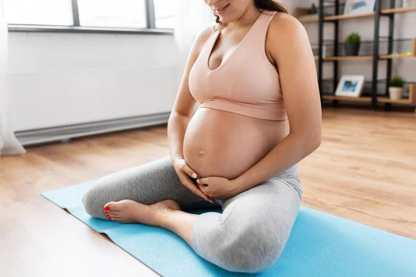 Close-up van zwangere vrouw doet yoga thuis — Stockfoto