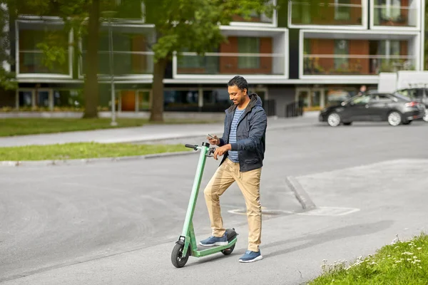 Людина зі смартфоном та електричним скутером у місті — стокове фото