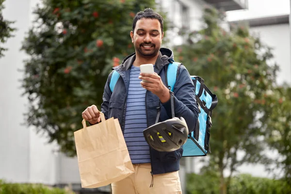 Repartidor con comida para llevar en bolsa y teléfono — Foto de Stock