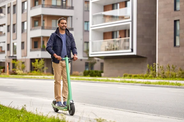 Щасливий усміхнений чоловік їде електричним скутером у місті — стокове фото