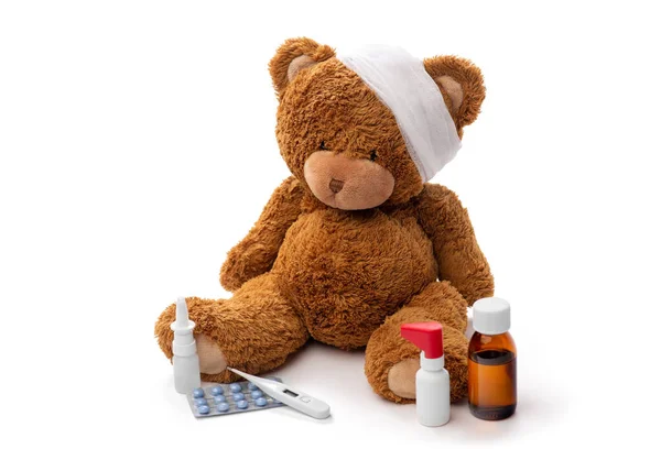 Teddy bear toy with bandaged head and medicines — Stock Photo, Image