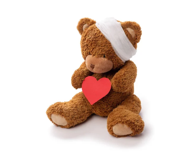 Teddy bear toy with bandaged head and red heart — Stock Photo, Image