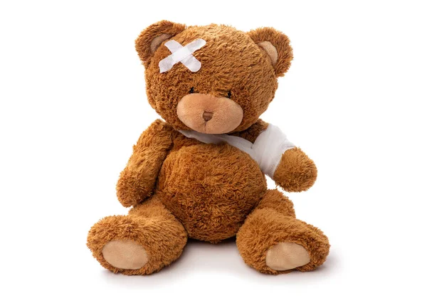 Teddy bear toy with bandaged paw and patch on head — Stock Photo, Image
