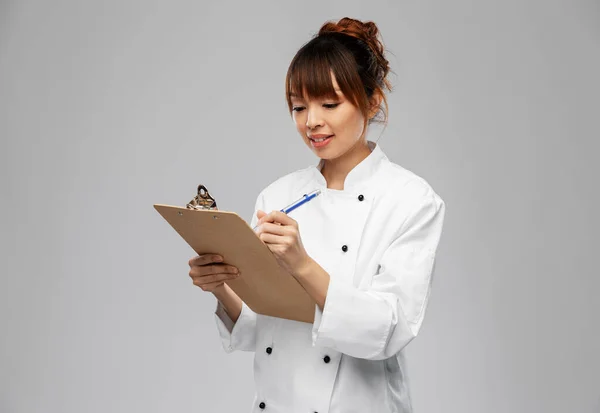 Χαμογελαστή γυναίκα σεφ με πρόχειρο και στυλό — Φωτογραφία Αρχείου