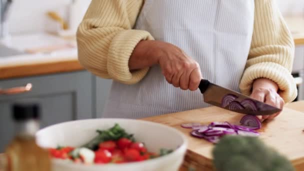 Kéz a nő vágás piros hagyma a konyhában — Stock videók