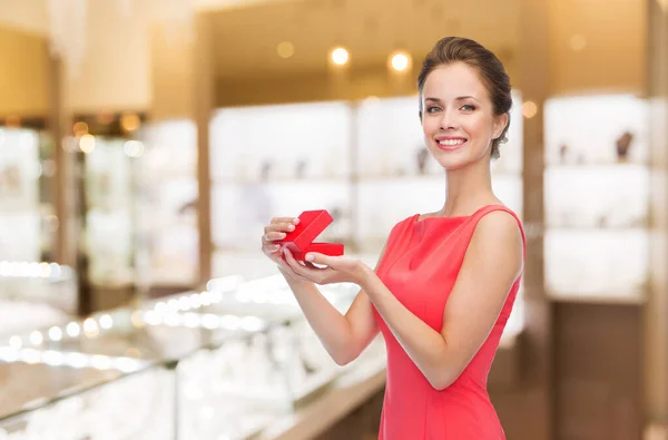 Glimlachende vrouw met rode geschenkdoos bij juwelier — Stockfoto