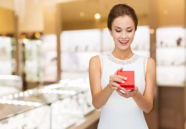 Mujer sonriente con caja de regalo roja en la joyería — Foto de Stock