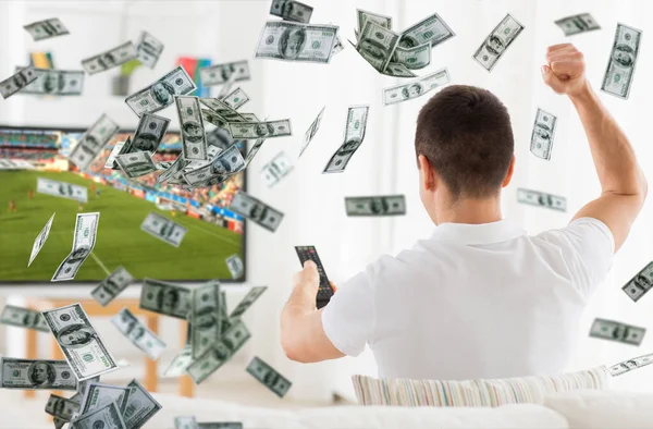 Hombre feliz viendo el partido de fútbol en la televisión sobre el dinero — Foto de Stock