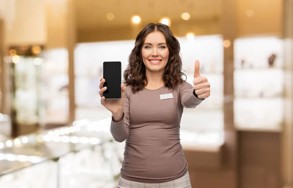 Asistente de tienda femenina feliz mostrando teléfono inteligente — Foto de Stock
