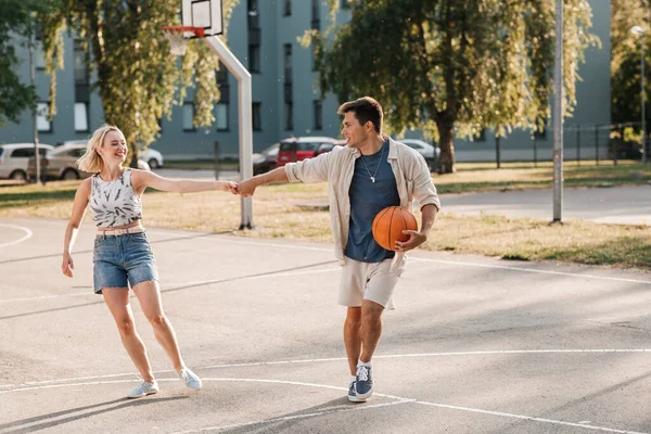 Couple heureux avec balle sur terrain de basket-ball — Photo