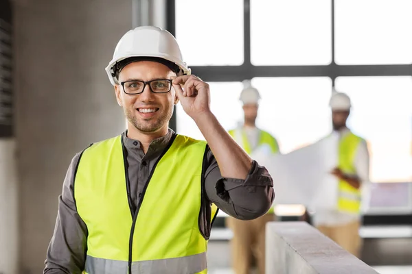 Architekt mit Helm und Sicherheitswesten im Büro — Stockfoto