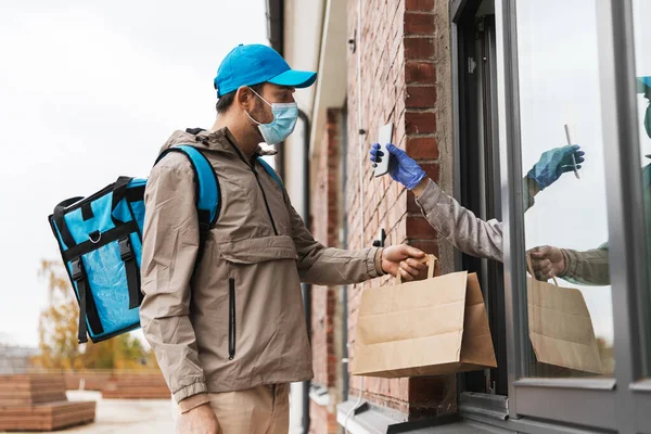 Food delivery man in mask giving order to customer — Stock Photo, Image