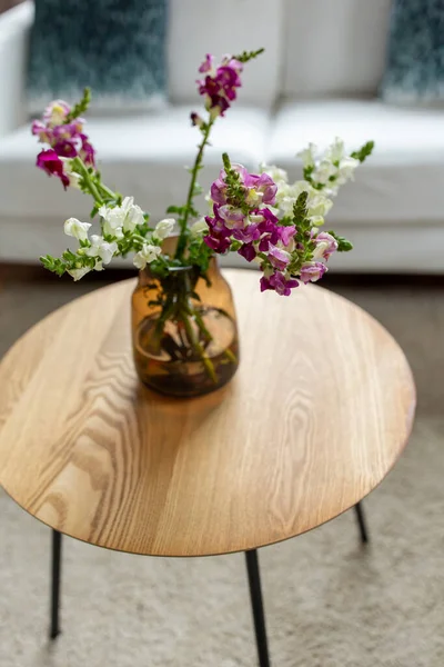 Bloemen in vaas op ronde salontafel thuis — Stockfoto