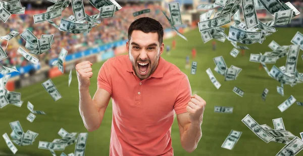 Щасливий чоловік з надмірною грошовою дощем на футбольному полі — стокове фото