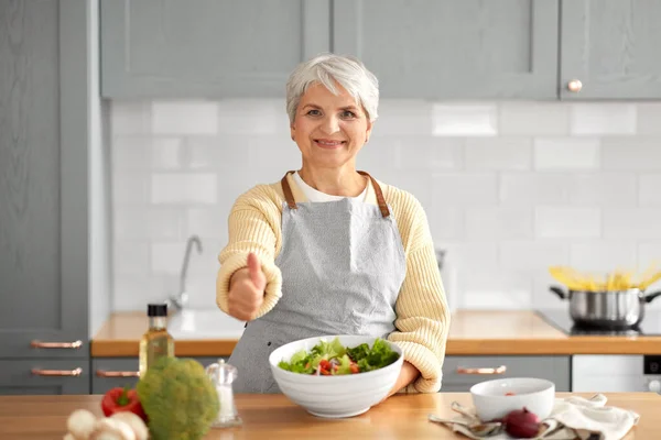 Boldog nő főzés saláta és mutatja hüvelykujját fel — Stock Fotó