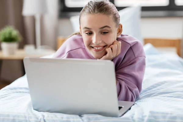 Lachende meisje met laptopcomputer thuis — Stockfoto