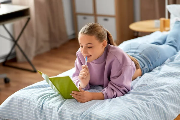 Myśląca dziewczyna z pamiętnikiem leżącym na łóżku w domu — Zdjęcie stockowe