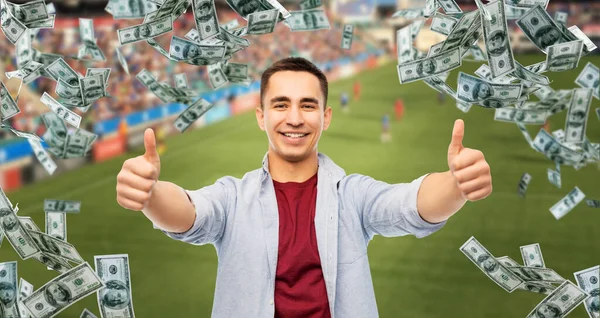 Чоловік показує великі пальці над грошима на футбольному полі — стокове фото