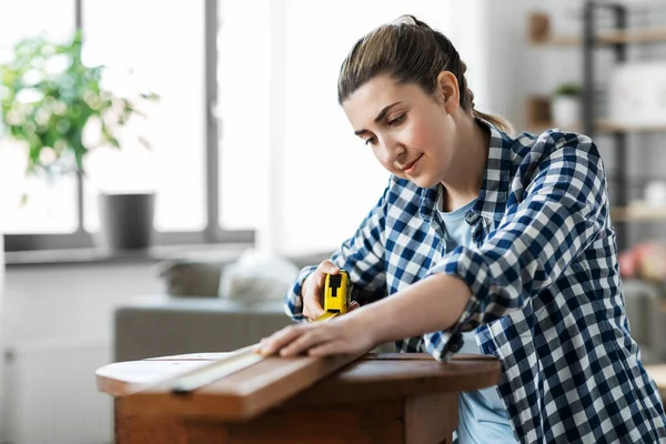 Mujer con regla que mide tablero de madera —  Fotos de Stock