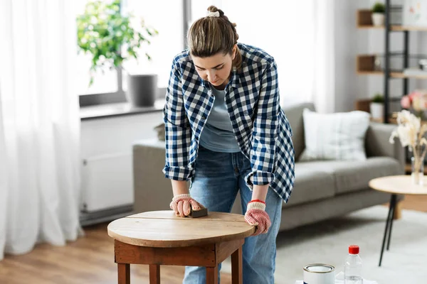 Mulher lixar mesa de madeira redonda velha com esponja — Fotografia de Stock