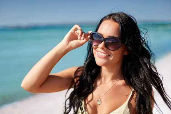 Smiling young woman in sunglasses on summer beach — Stock Photo, Image