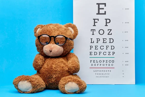 Ursinho de pelúcia brinquedo em óculos com gráfico de olho em azul — Fotografia de Stock