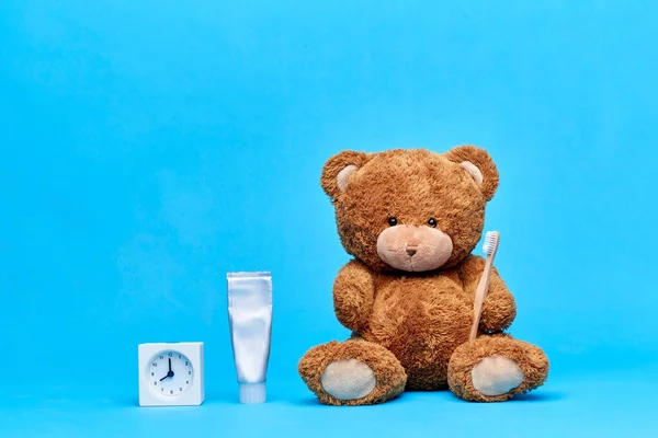 Ursinho de pelúcia com escova de dentes, pasta de dentes e relógio — Fotografia de Stock