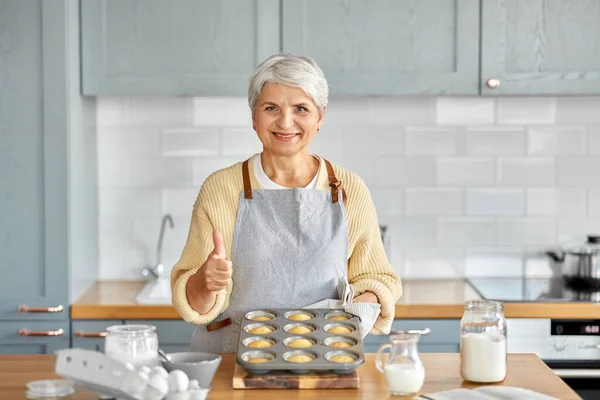 台所で型を焼くカップケーキを持つ女性 — ストック写真