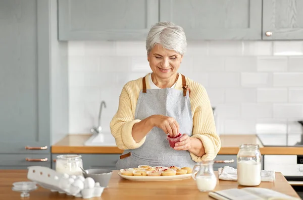 Kvinna dekorera muffins med bär på kök — Stockfoto