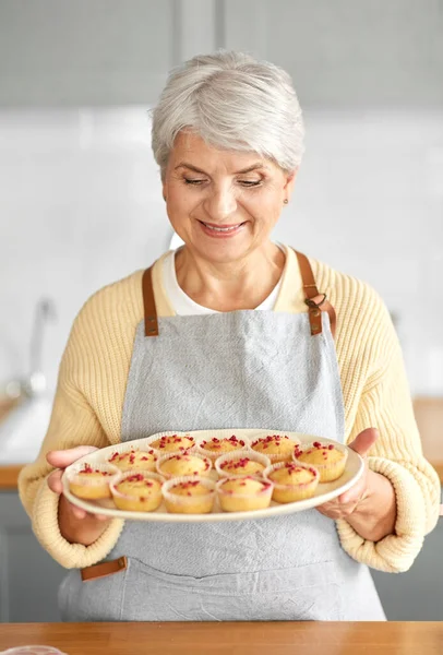 Mujer sosteniendo plato con cupcakes en la cocina — Foto de Stock