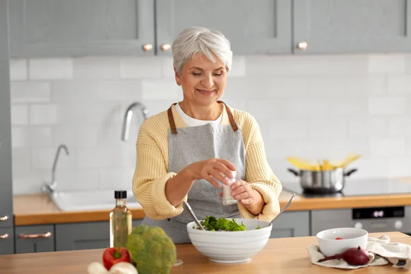 Щаслива жінка готує салат на кухні вдома — стокове фото