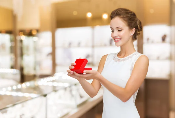 Mulher sorridente com caixa de presente vermelho na loja de jóias — Fotografia de Stock