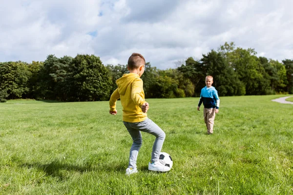 Meninos felizes com bola jogando futebol no parque — Fotografia de Stock