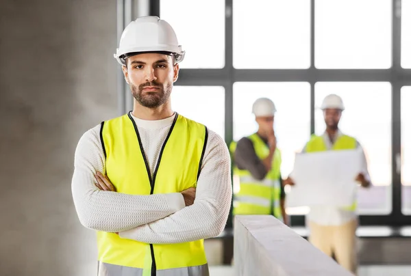 Arquiteto masculino em capacete e segurança oeste no escritório — Fotografia de Stock