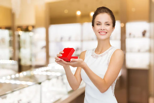 Donna sorridente con scatola regalo rossa in gioielleria — Foto Stock