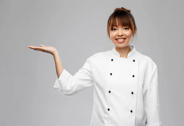 Glimlachende vrouwelijke chef houdt iets bij de hand — Stockfoto