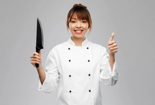 Улыбающаяся женщина-шеф-повар с ножом, показывающим большие пальцы вверх — стоковое фото