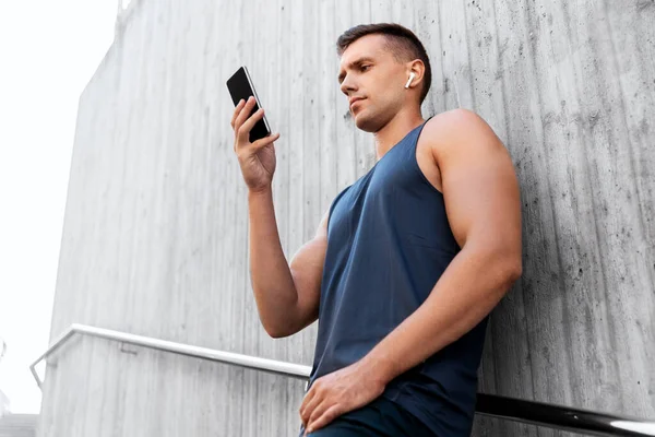 Jeune athlète homme avec écouteurs et smartphone — Photo